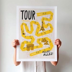 Unframed Tour cycling poster being held up, featuring a yellow winding race path on a neutral background, including fun illustrations of riders, fans and a selection of famous French landmarks.