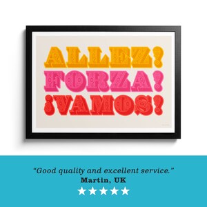 Op de afbeelding: Een ingelijste kunstdruk met drie regels tekst in een vet, decoratief lettertype. De bovenste regel toont ALLEZ! in geel, de middelste regel FORZA! in roze en de onderste regel VAMOS! in rood, alles tegen een lichte cr&egrave;mekleurige achtergrond.