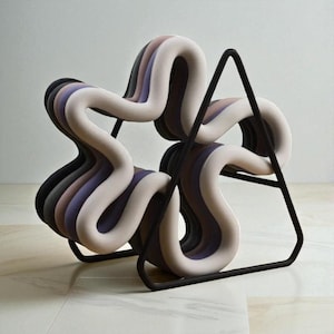 Puede incluir: Una silla moderna y única con un diseño floral. El asiento está compuesto por secciones curvas en capas en tonos de negro, gris, morado y beige. La silla está soportada por una estructura metálica negra, creando un mueble artístico y escultural.