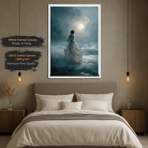 Op de afbeelding: Een ingelijste canvasprint toont een vrouw in een witte jurk te midden van stormachtige oceaangolven onder een maanverlichte hemel. Het kunstwerk is wit omlijst en bevat tekst: "White Framed Canvas Ready to Hang" en "100% Cotton Canvas (300 g/m&sup2;) Premium Print Quality."