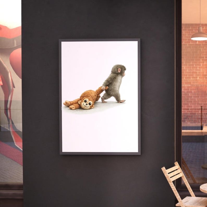 May include: Framed print showing a grey monkey pulling a brown stuffed monkey. The brown monkey lies on the ground, while the grey monkey walks forward. The artwork is set against a white background. The image is framed in black.