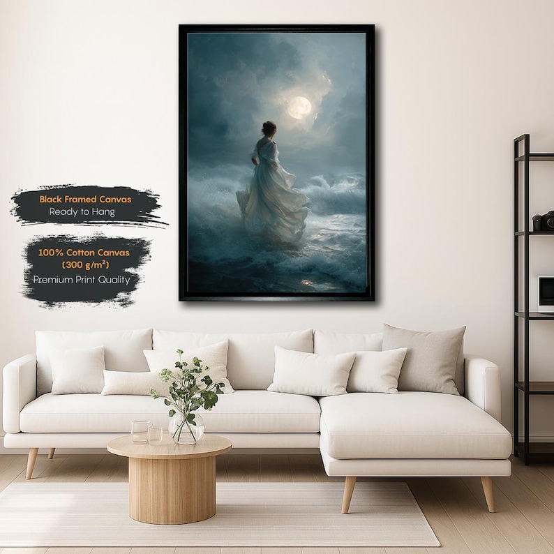 May include: Black framed canvas art print. The artwork depicts a woman in a flowing white dress standing in the ocean, facing a bright moon. The canvas is made of 100% cotton (300 g/m²) and is ready to hang.