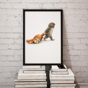 May include: A framed print showing a grey baby monkey walking and pulling a brown stuffed monkey. The artwork is displayed on a stack of books against a white brick wall. The image has a playful and whimsical theme.