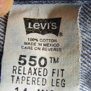 May include: Close-up of a Levi's tag on denim fabric. The tag is white with black text, including "Levi's", "550 Relaxed Fit Tapered Leg", and "100% Cotton Made in Mexico". The tag is stitched to the blue denim.