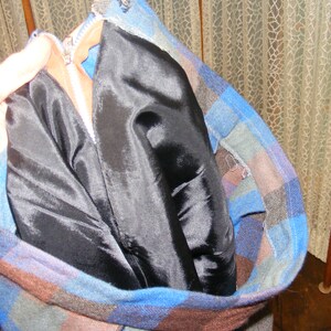 May include: A blue and brown plaid jacket with a black satin lining. The jacket is unzipped and the lining is folded over.