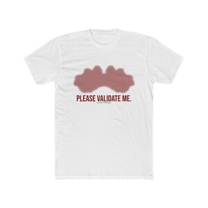 May include: White t-shirt with a maroon-colored abstract design and the text "PLEASE VALIDATE ME." The shirt is made of a soft, comfortable material. A casual, everyday wear tee.