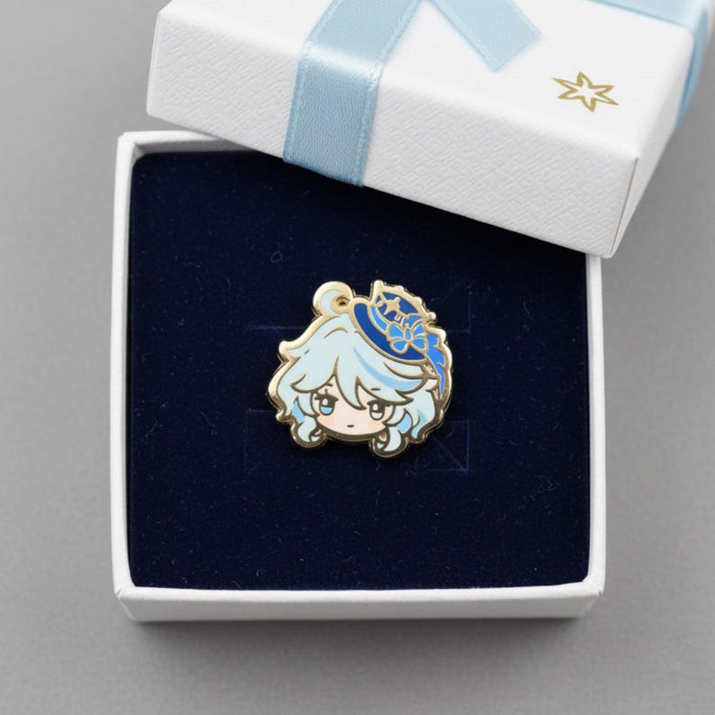 Peut inclure: &Eacute;pingle en &eacute;mail dor&eacute;e repr&eacute;sentant un personnage de dessin anim&eacute; aux cheveux bleu clair et un chapeau bleu. L'&eacute;pingle est pr&eacute;sent&eacute;e dans un coffret doubl&eacute; de velours bleu fonc&eacute;, avec un couvercle blanc nou&eacute; d'un ruban bleu clair.