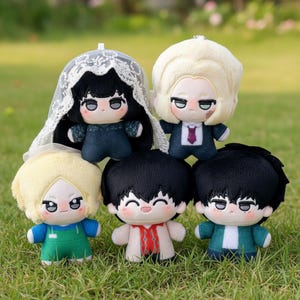May include: Six plush dolls with embroidered faces and different outfits. The dolls have black, blonde, and light brown hair. One doll wears a white veil, and another wears a suit with a purple tie. The dolls are arranged on green grass.