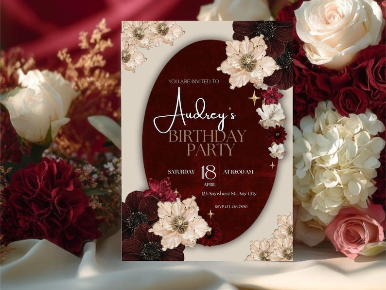 May include: A birthday party invitation with a burgundy oval design, adorned with cream and burgundy floral accents. The invitation reads "Audrey's BIRTHDAY PARTY" with the date, time, and location details. The background features a floral arrangement.