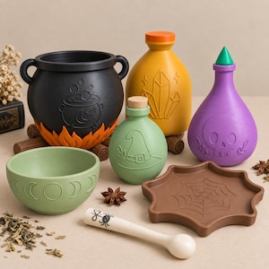 Peut inclure: Un ensemble d'objets décoratifs comprenant un chaudron noir sur des flammes orange, une bouteille jaune gravée de cristaux, une bouteille violette à tête de mort, une bouteille verte chapeau de sorcière, un bol phases lunaires, un plateau toile d'araignée et un pilon blanc.