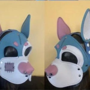 Puede incluir: Una m&aacute;scara de perro azul y blanco con detalles en rosa. La m&aacute;scara presenta orejas grandes, un hocico blanco y una nariz rosa. La m&aacute;scara tiene un dise&ntilde;o cosido y est&aacute; asegurada con remaches. La m&aacute;scara est&aacute; dise&ntilde;ada para ser usada.