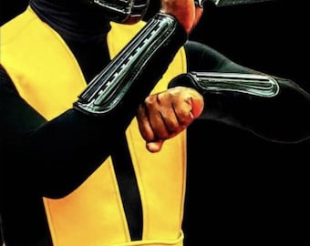 May include: A person in a black and yellow costume, with a black hood and a silver mask. The costume includes black sleeves with silver accents and a yellow sash. The person is holding a black weapon, with a black background.