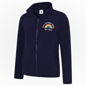 Könnte beinhalten: Marineblaue Fleecejacke mit durchgehendem Reißverschluss und hohem Kragen. Die Jacke hat ein Regenbogen-Design mit dem Text "Your Hospital Name" und "Your Name" in einem Halbkreis darüber und darunter.