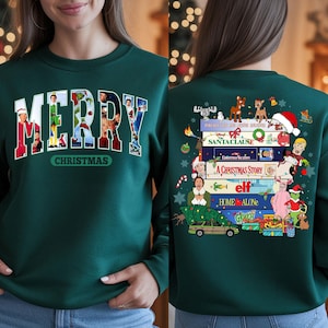 Puede incluir: Sudadera verde oscuro con la palabra "MERRY" en letras blancas con fotogramas de películas en su interior. La palabra "CHRISTMAS" está debajo. La parte trasera presenta títulos de películas como "Home Alone" y "Elf" con personajes navideños.