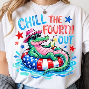 May include: White t-shirt with a colorful graphic of an alligator in sunglasses and a pink hat, relaxing on a red, white, and blue inner tube. The text reads "CHILL THE FOURTH OUT" with star accents, perfect for Independence Day celebrations.