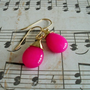 May include: A pair of gold earrings with pink teardrop-shaped stones.