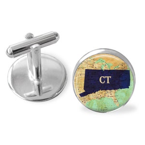 May include: Silver cufflinks featuring a round, vintage-style map of the United States. The state of Connecticut is highlighted in blue with the abbreviation "CT" in gold lettering.