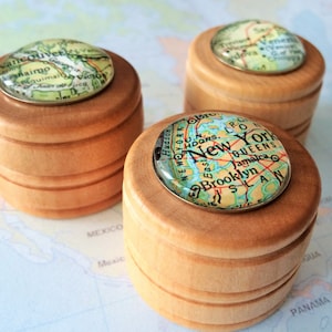 May include: Three wooden boxes with map-themed lids. The lids feature maps of Vancouver, New York City, and a third city that is not visible in the image.
