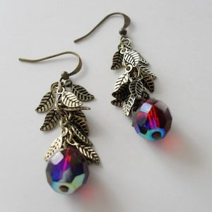 May include: A pair of dangle earrings with a red iridescent glass bead and gold tone leaf charms.