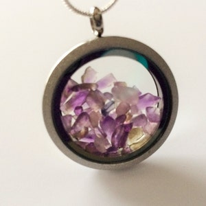 May include: A silver locket necklace with a clear glass insert filled with small purple and clear crystals.