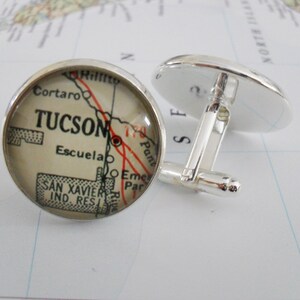 May include: Silver cufflinks with a round glass cabochon featuring a vintage map of Tucson, Arizona. The map shows the city's streets and landmarks, including the words "TUCSON" and "Escuela".