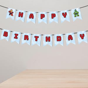以下が含まれることがあります： 「HAPPY BIRTHDAY」の文字が赤い文字で書かれた、水色のペナントの飾り。スーパーヒーローのイラストが描かれています。誕生日のパーティーに最適です。