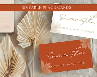 May include: Two rectangular place cards featuring the name Samantha and the text Grateful to be together. One card has a white background with gold leaf accents, and the other has a burnt orange background with light orange leaf illustrations.