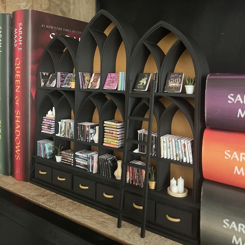Gothic dollhouse bookcase with arches and drawers displayed in a moody styled interior, miniature 1:12 scale library wall