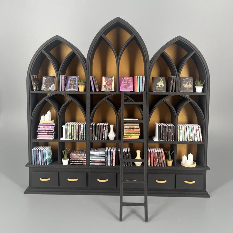 Black gothic miniature bookcase with three cathedral arches and ladder, fully styled with tiny books and plants on grey background