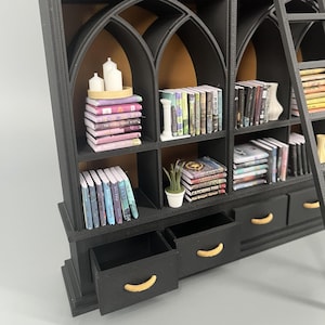 Side angle of 1:12 gothic dollhouse library showing shelf depth, removable drawers with gold handles and arched shelving