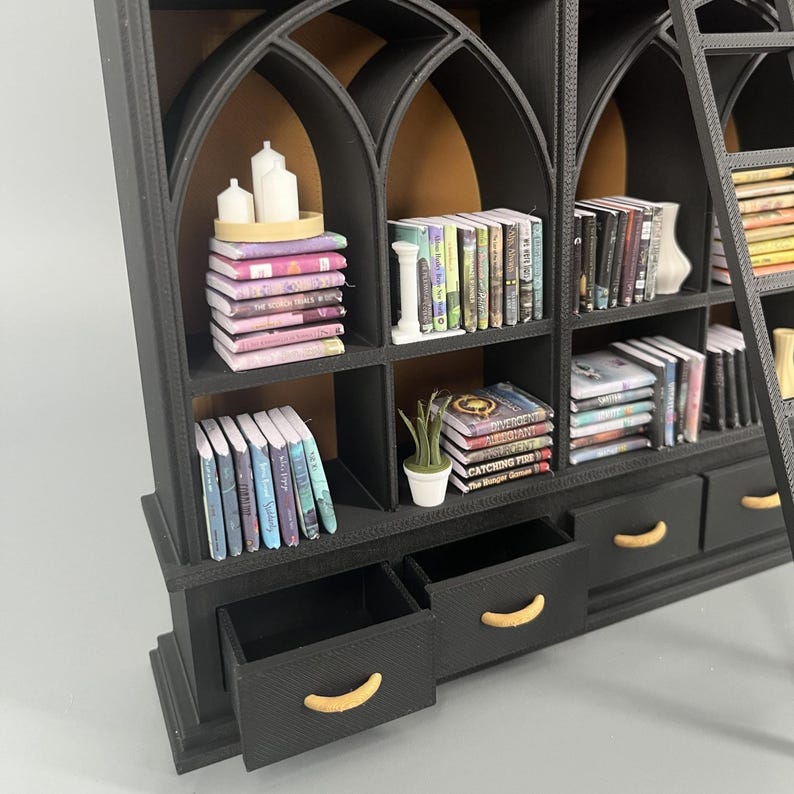 Side angle of 1:12 gothic dollhouse library showing shelf depth, removable drawers with gold handles and arched shelving