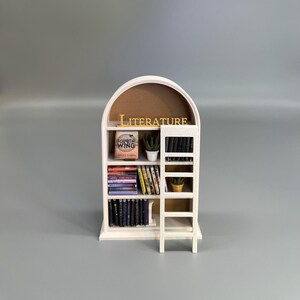 Arched miniature bookcase with ladder on neutral grey backdrop