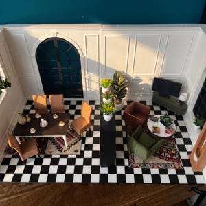 Könnte beinhalten: Ein Miniatur-Raumset mit schwarz-weiß kariertem Boden, weißen getäfelten Wänden und einem Bogenfenster. Der Bereich umfasst ein Esszimmer mit einem dunklen Tisch und vier beigen Stühlen sowie einen Wohnbereich mit braunen und grünen Sesseln.