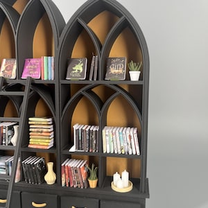 Detail of gothic dollhouse bookcase arches and shelving with miniature books and ladder, black and gold 1:12 scale library