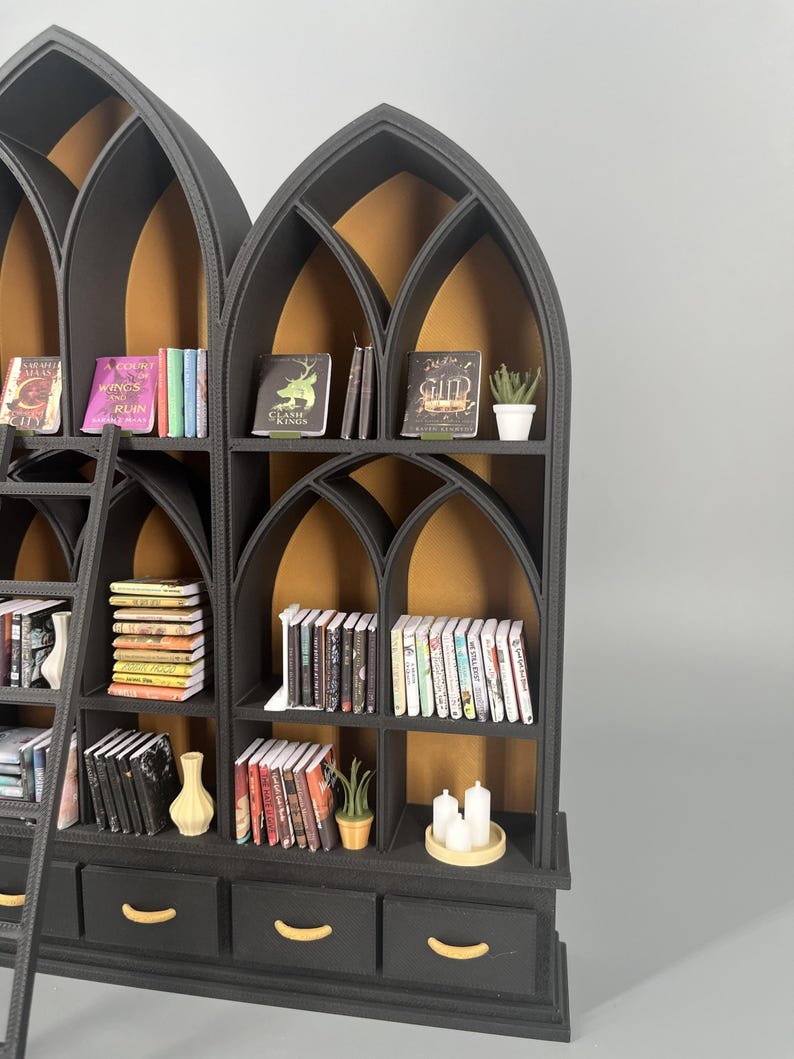 Detail of gothic dollhouse bookcase arches and shelving with miniature books and ladder, black and gold 1:12 scale library