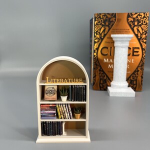 Miniature arched bookcase styled next to large novel for size comparison