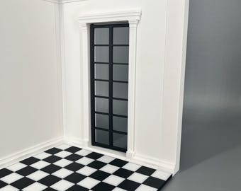 Könnte beinhalten: Ein Miniatur-Raumeckmodell mit weißen Wänden, dekorativen Leisten und einer hohen, schmalen, schwarz gerahmten Tür mit mehreren Glasscheiben. Der Boden ist mit einem schwarz-weißen Schachbrettmuster versehen, das einen starken Kontrast bildet.