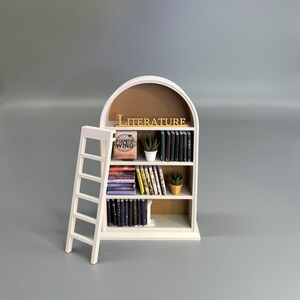 Miniature bookcase with ladder on grey background side angle