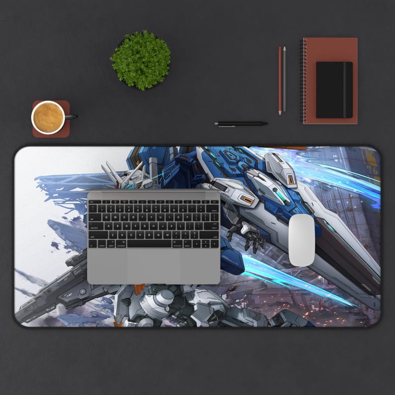 K&ouml;nnte beinhalten: Eine rechteckige Schreibtischunterlage mit einer detaillierten Illustration eines blauen, wei&szlig;en und grauen Mecha-Roboters. Ein silberner Laptop, eine wei&szlig;e Maus und eine Tastatur befinden sich auf der Unterlage. Eine Tasse Kaffee, eine kleine Pflanze und ein Notizbuch sind ebenfalls zu sehen.