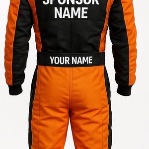 May include: Orange and black racing suit with the text "YOUR SPONSOR NAME" on the back and "YOUR NAME" on the waist. The suit features a German flag patch on the upper back and black accents.