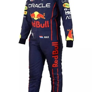 May include: Navy blue racing suit with red and white sponsor logos, including "Oracle" and "Red Bull." The suit features a full-body design with long sleeves and legs, and a Mandarin collar. The suit has a zipper closure and is designed for motorsports.