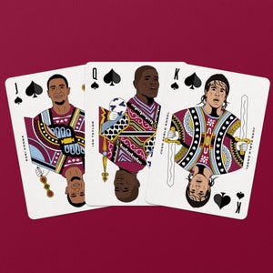 以下が含まれることがあります： サッカー選手が描かれた3枚のトランプ。スペードのジャックはエズリ・コンサ、スペードのクイーンはサッカーボールを持つイアン・テイラー、スペードのキングは剣を持つフアン・パブロ・アンヘルが描かれています。
