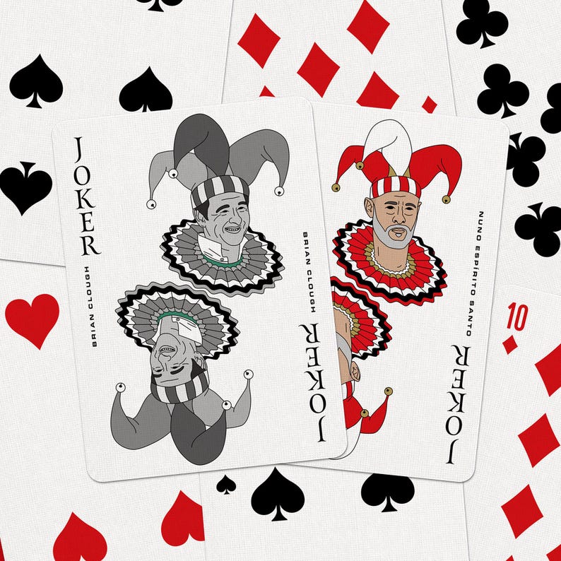 May include: Playing cards featuring two Joker cards with illustrations of Brian Clough and Nuno Esp&iacute;rito Santo. The cards are white with black text and colorful jester designs. Other playing cards with suits of hearts, spades, diamonds, and clubs are scattered around.