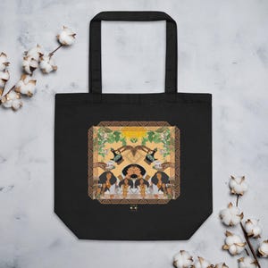 May include: Black tote bag with a colorful illustration. The artwork features figures with dark hair, holding cups, and surrounded by floral and geometric patterns. The bag has two black handles.