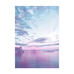 May include: A serene landscape photograph featuring a pier extending into a body of water. The sky transitions from blue to pink, with soft clouds. The water reflects the sky's colors, creating a tranquil scene. A building is visible on the pier.