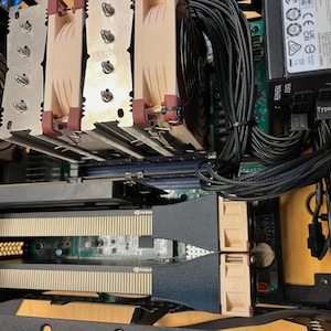 Könnte beinhalten: Nahaufnahme der internen Komponenten eines Computers. Das Bild zeigt einen CPU-Kühler mit mehreren Lamellen, eine Grafikkarte und verschiedene Kabel. Das Farbschema umfasst Beige, Schwarz und Silber.