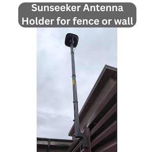 May include: A dark gray Sunseeker antenna mounted on a pole, designed for fence or wall installation. The antenna is topped with a black, square-shaped component. The image includes the text "Sunseeker Antenna Holder for fence or wall".