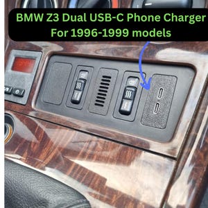 Puede incluir: Un panel negro con dos puertos USB-C, parte del interior de un coche BMW Z3. El panel también cuenta con botones para asientos con calefacción y otros controles. Se muestra el texto "BMW Z3 Dual USB-C Phone Charger For 1996-1999 models".