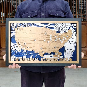 May include: A framed wooden baseball stadium map with a detailed cutout of the United States. The map includes baseball stadium locations, the Dodgers logo, and the text "BASEBALL STADIUM MAP". The frame is black, with blue and white accents.