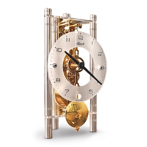 May include: A silver and clear acrylic mantel clock with a gold pendulum and visible gears. The clock face is white with black hands and numerals. The clock has a rectangular shape and stands on four silver legs.